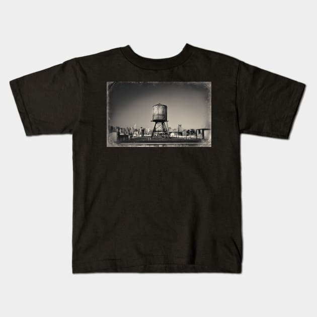 Sepia-toned image of a rusty water tower on a rooftop of Queens, in New York City, with the Queensboro Bridge and the Manhattan skyline in the background. Kids T-Shirt by Reinvention